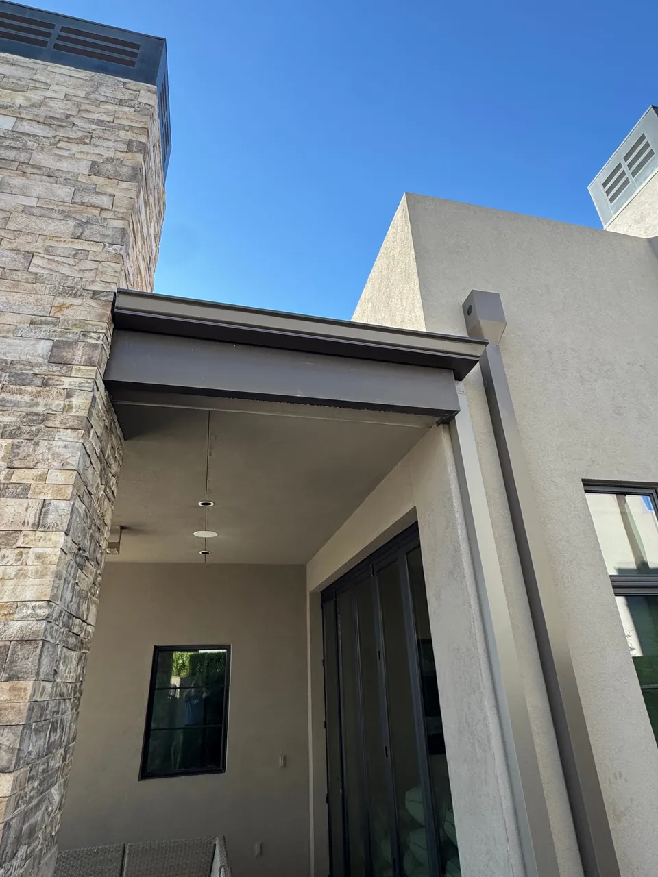 Dark seamless gutters on a modern stone and stucco home