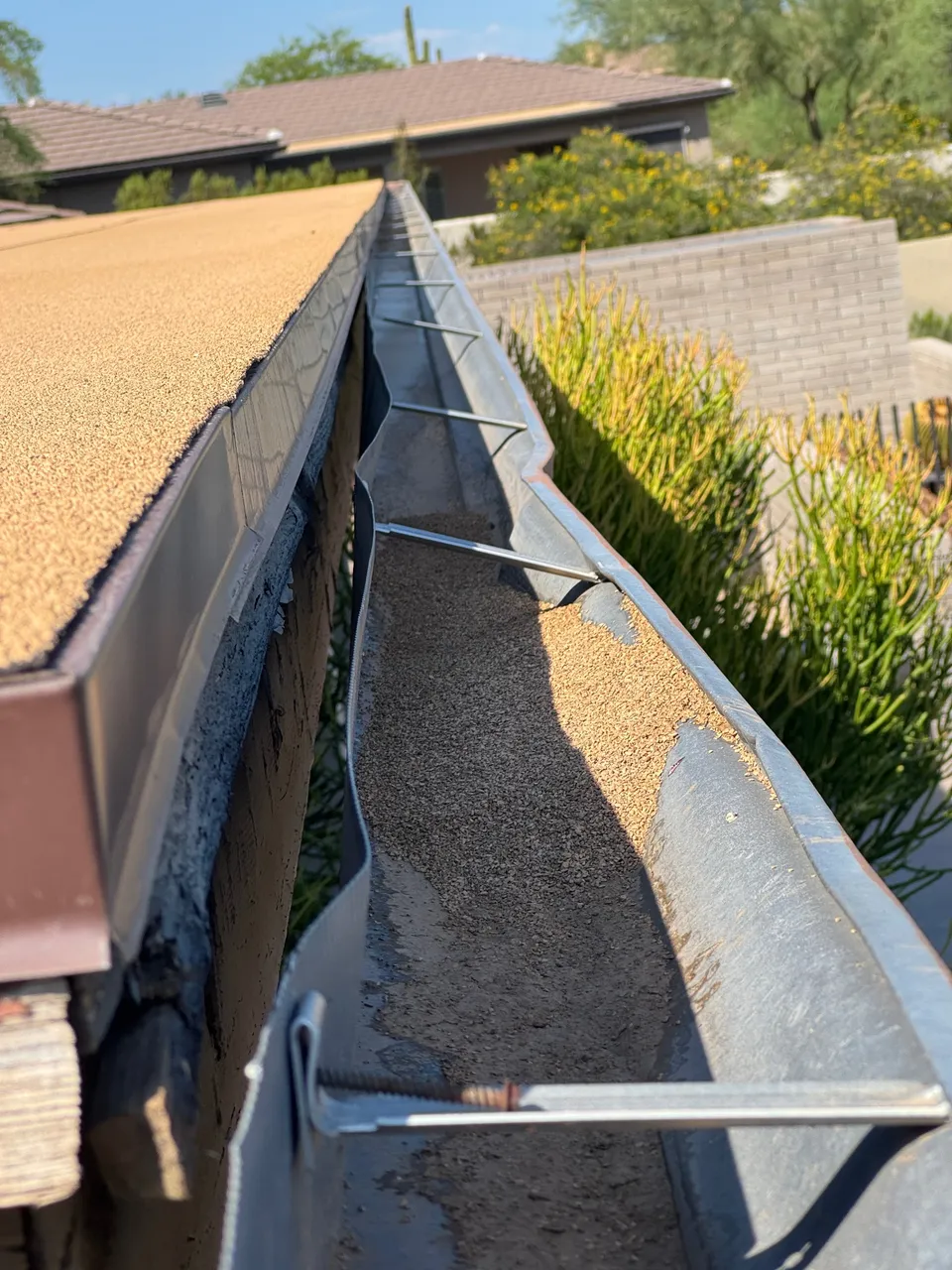 A gutter trough filled with desert sand and dust on a Phoenix home before cleaning