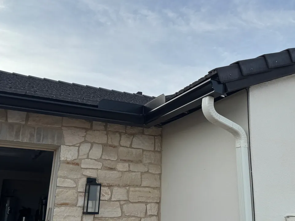 Seamless gutter corner and downspout on a stone veneer home