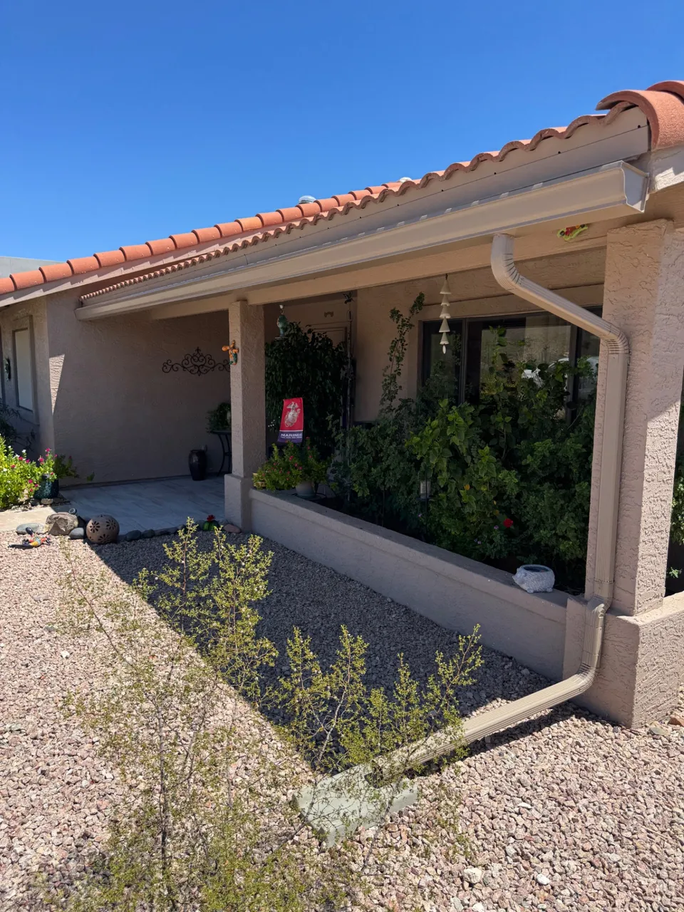 Seamless gutters on a tile-roof home with a covered patio and desert landscaping