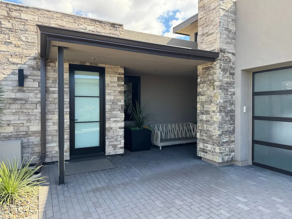 Seamless gutters on a modern home entry with stone columns and a paver driveway