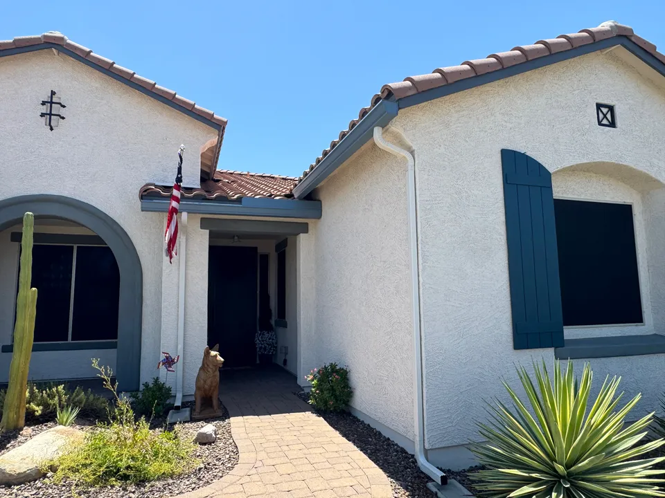 A stucco home with a tile roof, new seamless gutters and a downspout at the entry